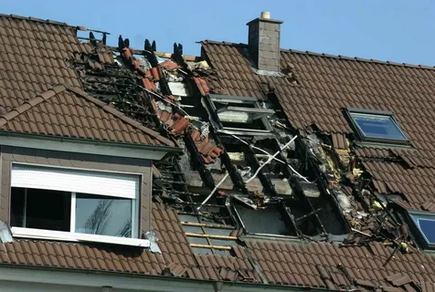 Tiled roof torn open with exposed rafters and damaged skylights, showing why hail damage roof repair matters